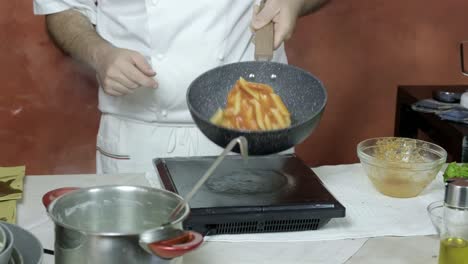 Chef-pours-vegetable-sauce-mixture-into-deep-pan-with-penne-pasta-shaking-to-mix