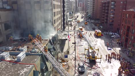 Drone-flies-in-circle,-firefighters-put-out-fire-on-street-building-in-Montreal,-Quebec,-Canada