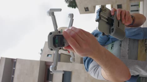 Vertical-footage-of-male-drone-pilot-launching-a-quadcopter-from-his-hand