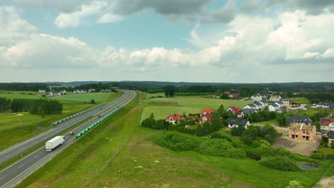 Malerische-Aussicht-Auf-Eine-Autobahn,-Die-Durch-Die-Polnische-Landschaft-Mit-Häusern-Und-Grünen-Feldern-Unter-Einem-Teilweise-Bewölkten-Himmel-Führt