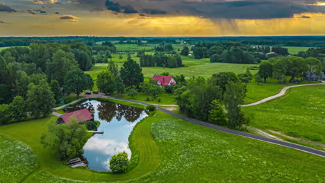 Aerial-drone-shot-over-smoke-coming-out-of-a-village-house-surrounded-by-green-grasslands-on-a-cloudy-day-in-timelapse