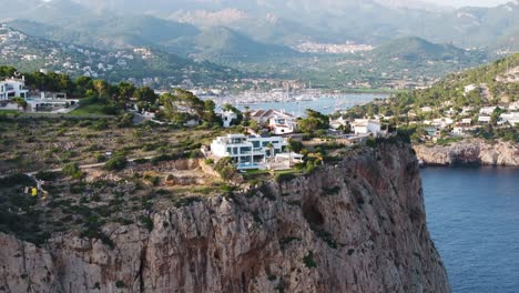 Slow-aerial-ascend-near-rugged-seaside-cliff-with-buildings,-Mallorca