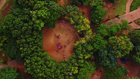 Top-down-aerial-of-a-large-crowd-in-an-open-place-surrounded-by-green-trees-in-a-beautiful-park-in-Abuja,-Nigeria