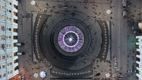 Overhead-aerial-riser-above-circular-bronze-fountain-on-Piazza-de-Ferrari,-Genoa