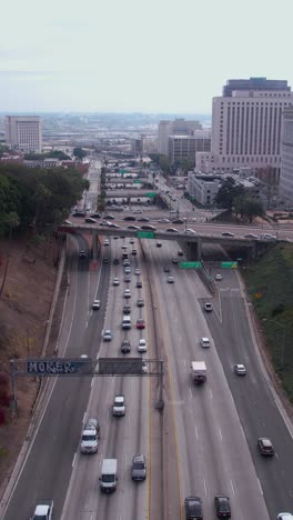 Los-Angeles-USA,-Vertical-Aerial-View-of-US-101-Highway-Traffic-by-Downtown-Buildings,-Drone-Shot