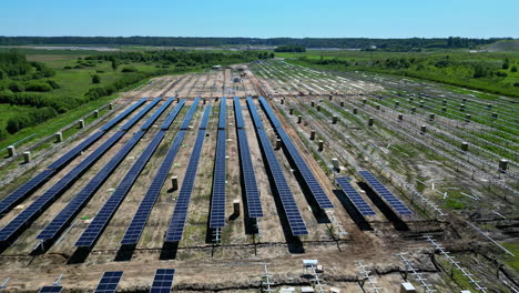 Aerial-drone-panning-shot-from-right-to-left-over-newly-constructed-solar-panels-on-a-sunny-day-along-rural-countryside