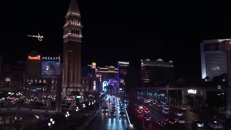 NIght-Traffic-on-Las-Vegas-Strip-Between-Mirage-and-Venetian-Casino-Hotels,-Lights-and-Billboards,-Nevada-USA