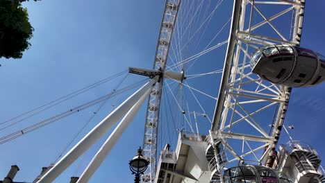 The-london-eye-ferris-wheel-is-standing-tall-against-a-bright-blue-sky,-offering-a-glimpse-of-the-passenger-capsules