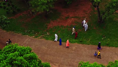 Hermosa-Antena-De-Personas-Vestidas-Con-Ropa-Tradicional-Africana-Caminando-Por-Un-Parque-Verde-En-Abuja,-Nigeria