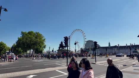 View-of-Westminster-Bridge,-with-people,-traffic-lights,-and-the-London-Eye-in-the-background-on-a-bustling-day