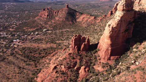 Vista-Aérea-De-Formaciones-Rocosas-Rojas-Y-Colinas-Sobre-Casas-En-Los-Suburbios-De-Sedona,-Arizona,-EE.UU.