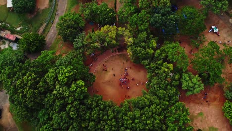 Top-down-overview-of-a-beautiful-green-park-with-people-playing-on-an-open-space-between-the-trees