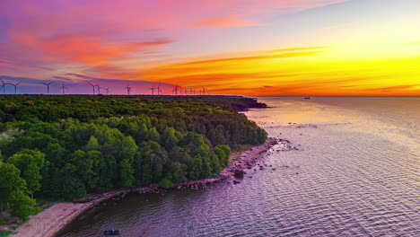 Vegetated-Shoreline-With-Rotating-Wind-Turbines-In-The-Background-During-Sunset