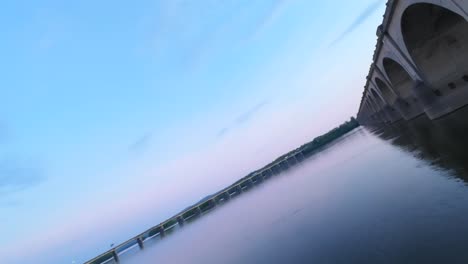 Drone-flight-below-bridge-with-arches-during-golden-sunset-time