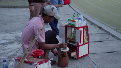 Street-vendor-preparing-rujak,-an-Indonesian-fruit-dish,-at-a-public-park-in-Tangerang