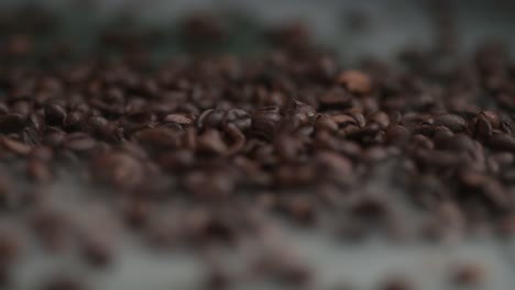 Close-up-coffee-beans-falling,-spilling-onto-the-table-into-smoke,-fog