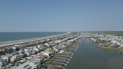 4k-rising-drone-shot-of-beach-houses-on-a-bright-day-with-blue-skies