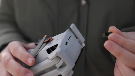 Close-up-of-hands-inserting-a-micro-SD-memory-card-into-slot-on-drone