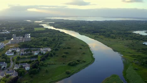 Aerial-view-of-River-Corrib-to-lake-as-sunset-golden-sky-reflects-in-calm-water