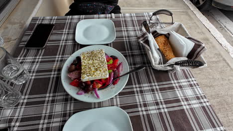 Ensalada-Griega-En-La-Mesa-Del-Restaurante,-Queso-Feta-Con-Orégano-Y-Aceite-De-Oliva