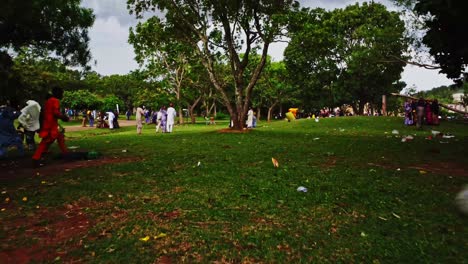 People-quickly-walking-through-a-park-while-strong-winds-rustle-the-green-trees-indicating-a-storm-coming