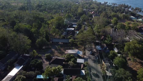 Tulamben,-bali-village-surrounded-by-lush-greenery-and-coastline,-aerial-view