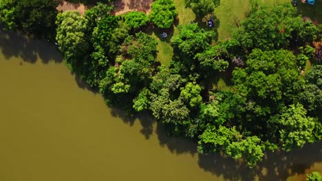 Top-down-aerial-of-a-beautiful-green-park-alongside-a-large-lake-in-Abuja,-Nigeria