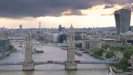 Sonnenuntergangs-Drohnenaufstieg-Zeigt-Londons-Stadtbild-Mit-Roten-Bussen,-Die-Die-Tower-Bridge-überqueren