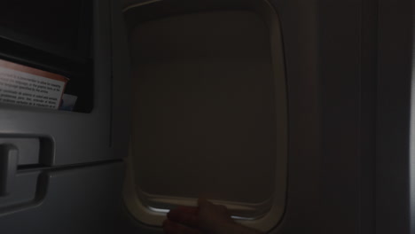 Hand-closing-airplane-window-to-sleep,-world-travel-concept