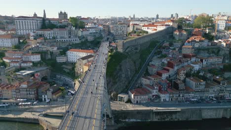 4k-rotating-drone-shot-of-the-Dom-Luis-I-bridge-at-sunset-in-Porto,-Portugal-as-people-walk-across