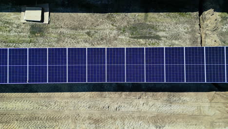 Aerial-drone-top-down-shot-over-workers-constructing-new-solar-panels-for-renewable-energy-generation-on-a-sunny-day