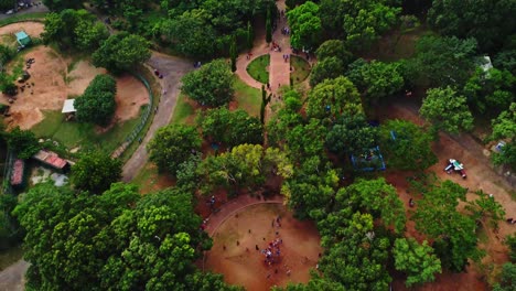 High-angle-tilt-down-to-people-playing-in-a-beautiful-green-park-in-Abuja,-Nigeria