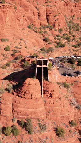 Vertical-Aerial-View,-Chapel-of-Holy-Cross-and-Visitors,-Landmark-Under-Red-Rocks,-Sedona-Arizona-USA