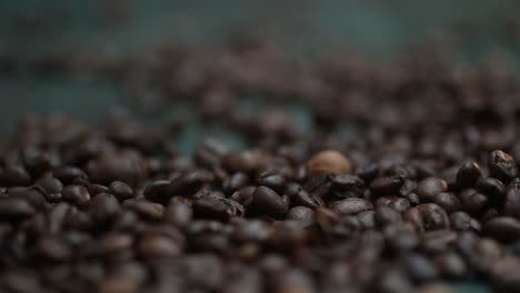 Close-up-time-lapse-coffee-beans-falling,-spilling-onto-the-dark-green-table