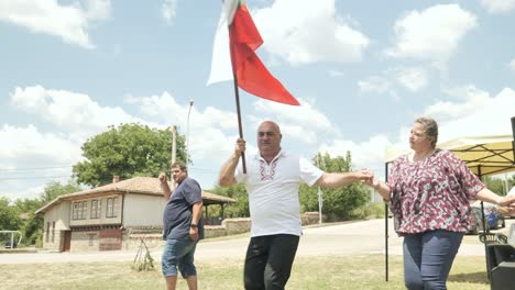 Bulgarian-village-mayor-holds-flag-dancing-horo-at-folk-festival