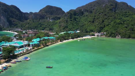 El-Agua-Turquesa-Baña-Suavemente-La-Costa-De-Una-Isla-Tropical,-Con-Barcos-Salpicando-El-Paisaje-Marino-Y-Exuberantes-Colinas-Verdes.