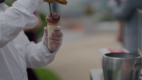 Server-topping-chocolate-ice-cream-cone-with-chocolate-syrup-at-an-event