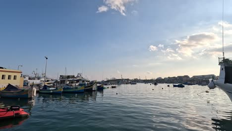 Una-Vista-Panorámica-De-Un-Tranquilo-Puerto-En-Malta,-Con-Barcos-Pesqueros-Y-Turísticos-Flotando-Suavemente-Durante-El-Día.