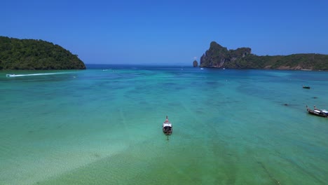 Koh-Phi-Phi-Bay,-colorful-traditional-longtail-boats-are-floating-on-calm-turquoise-water