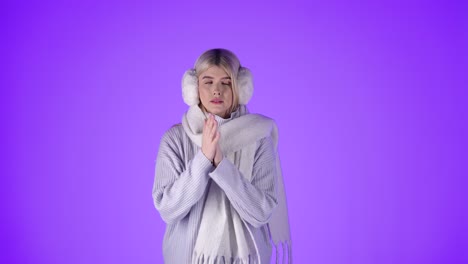 Blonde-Woman-Feeling-Cold-Rubbing-Hands-To-Warm-Up,-Dressed-In-Winter-Clothes,-Studio-Shot-With-Purple-Background