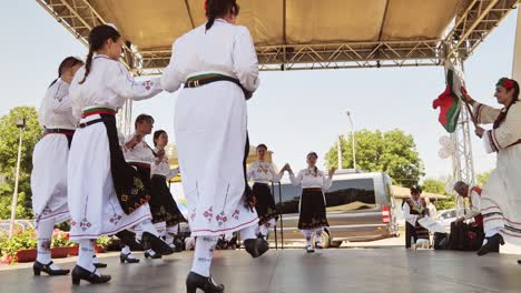 Ladies-Bulgarian-folk-dance-group-stage-performance-with-national-flag