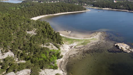 Vista-Aérea-De-La-Isla-Saltö-En-Suecia-Que-Muestra-Una-Costa-Rocosa,-Un-Denso-Bosque-Y-Aguas-Tranquilas.