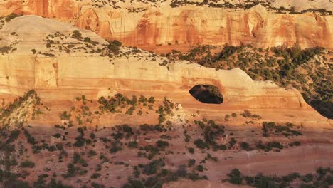 Natural-arch-in-sunlit-red-rock-cliffs-near-Moab,-Utah,-creating-a-striking-desert-landscape