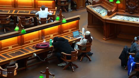 Tired-students-sitting-in-front-of-the-desk-in-the-grand-La-Trobe-Reading-Room-at-the-State-Library-Victoria,-in-Melbourne's-central-business-district,-concept-shot-of-Australian-students-HECS-debt