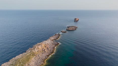 Aerial-view-of-Punta-de-El-Toro-narrow-rock-path-in-calm-sea,-Mallorca