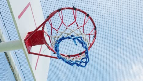 Basketball-Hoop-With-Blue-Sky-And-Covered-By-The-Net-To-Protect-A-Ball-To-Be-Lost-On-A-Cruise-Ship-Deck,-Low-Angle-View