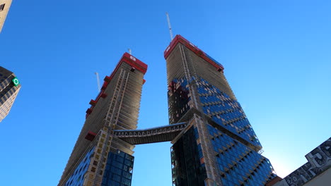 Residential-Towers-Under-Construction-Connected-By-Aerial-Skybridge,-Low-Angle