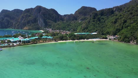 El-Agua-Turquesa-Baña-Suavemente-La-Costa-De-Una-Isla-Tropical,-Con-Barcos-Salpicando-El-Paisaje-Marino-Y-Exuberantes-Colinas-Verdes.