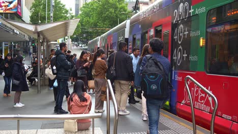 Tram-arrived-at-Bourke-street-mall-tram-stop-with-passengers-disembarking-and-boarding-the-tram-in-the-bustling-Melbourne's-Central-Business-District,-city-center-with-influx-of-population