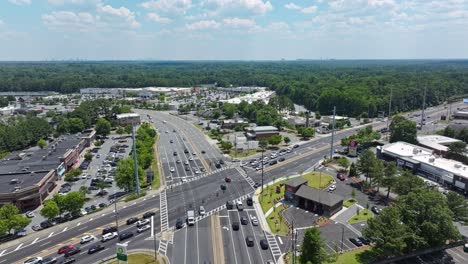 Aerial-backwards-shot-of-busy-junction-on-interstate-in-american-suburb